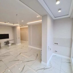 Michał Majewski - Jasne, przestronne wnętrze po remoncie z marmurową podłogą, oświetleniem LED i dekoracyjnymi panelami ściennymi.