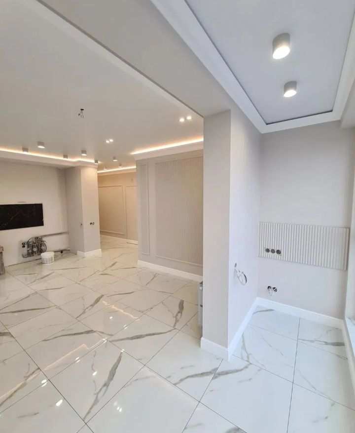 Jasne, przestronne wnętrze po remoncie z marmurową podłogą, oświetleniem LED i dekoracyjnymi panelami ściennymi.