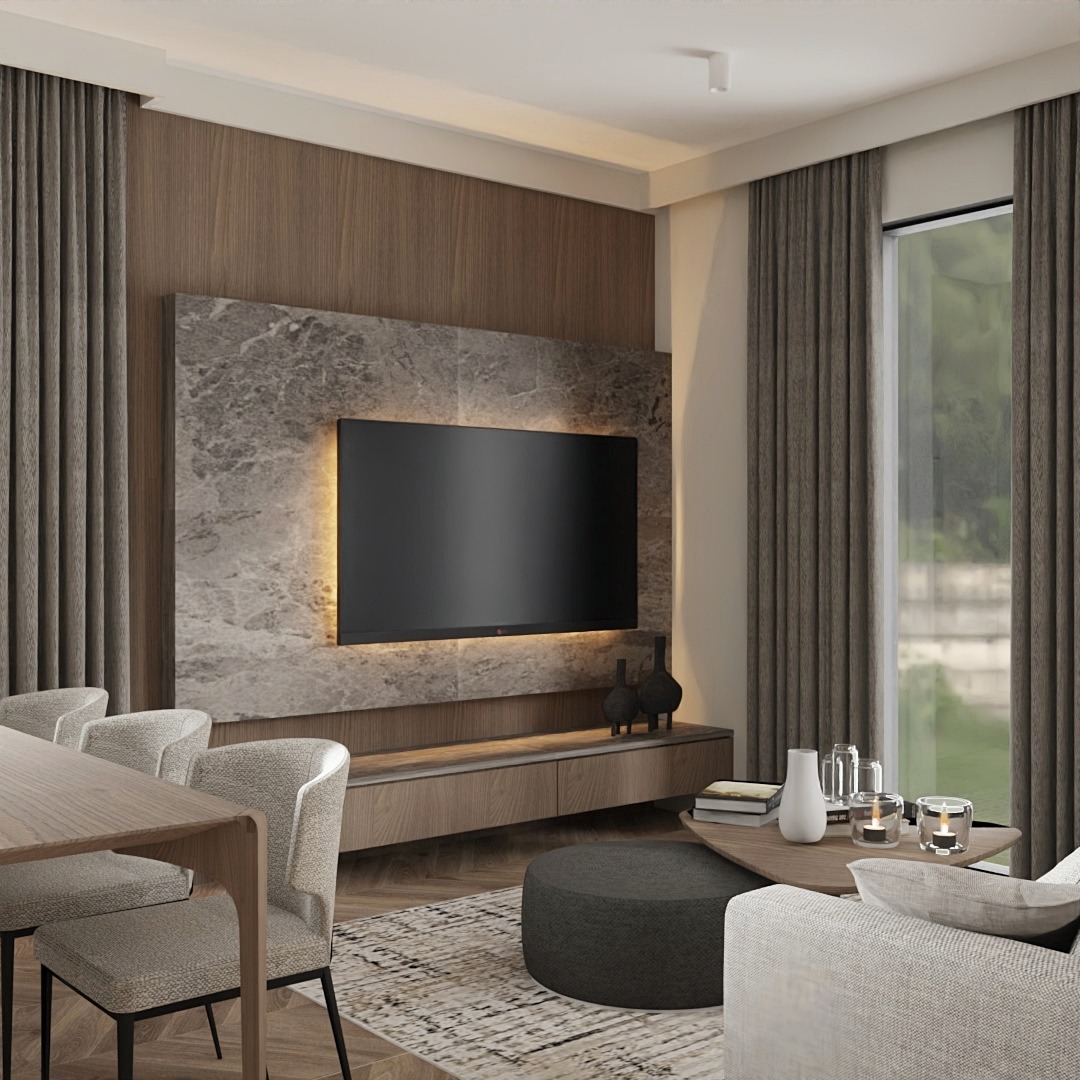 Nowoczesny salon z telewizorem na ścianie z marmurowym panelem, drewnianą szafką RTV, okrągłym pufem i zasłonami w kolorze taupe, widok na stół jadalny z krzesłami.