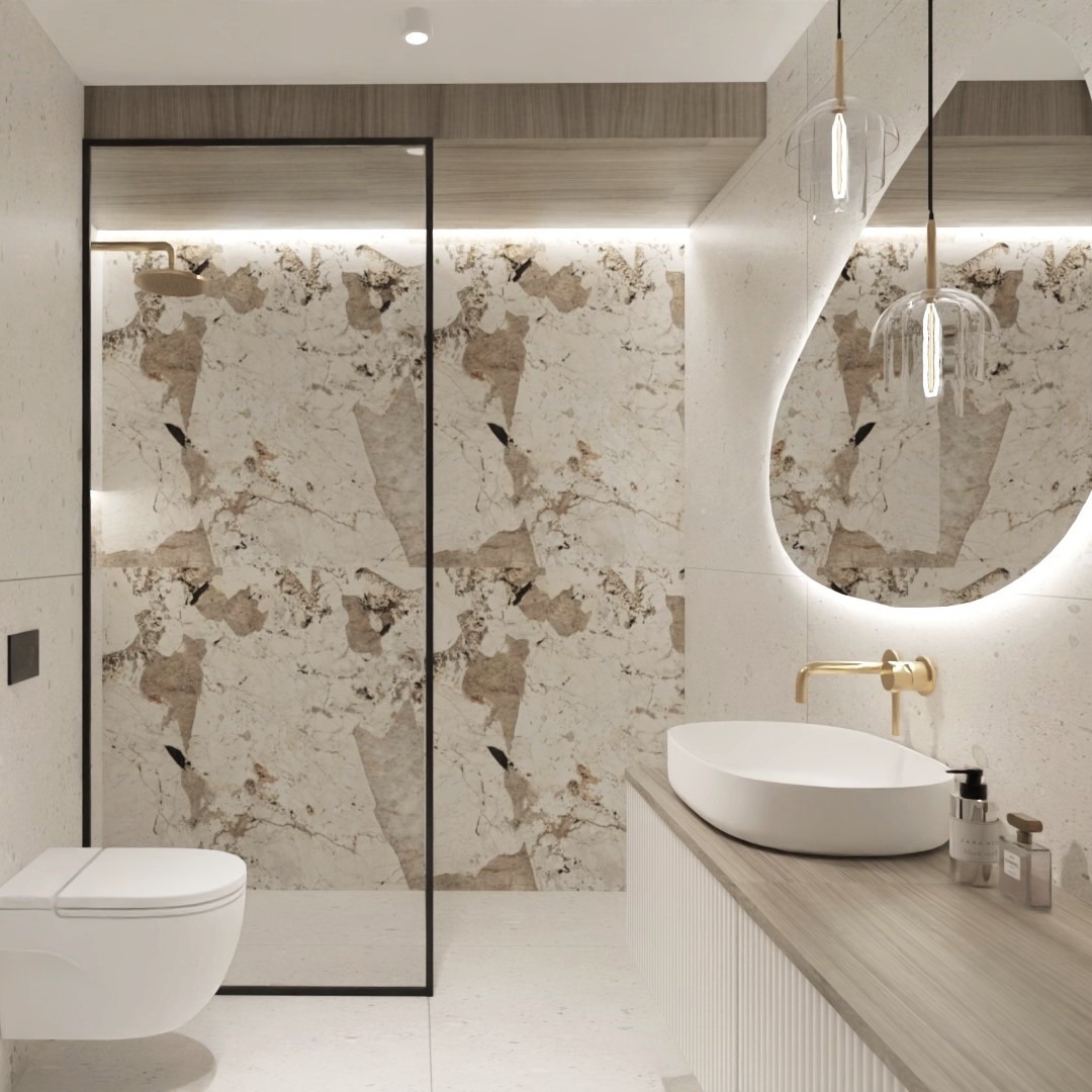 Elegancka łazienka z kabiną prysznicową typu walk-in, marmurowymi płytkami, owalnym lustrem z podświetleniem LED, białą umywalką nablatową z złotą baterią i minimalistyczną toaletą podwieszaną.