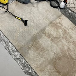 BubbleB - Beżowy dywan z wzorem w trakcie czyszczenia, widoczne plamy i urządzenia czyszczące na folii ochronnej.