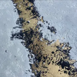 Fragment ściany z dekoracyjnym tynkiem w odcieniach szarości i złota, z wyraźną fakturą i nieregularnymi wzorami.