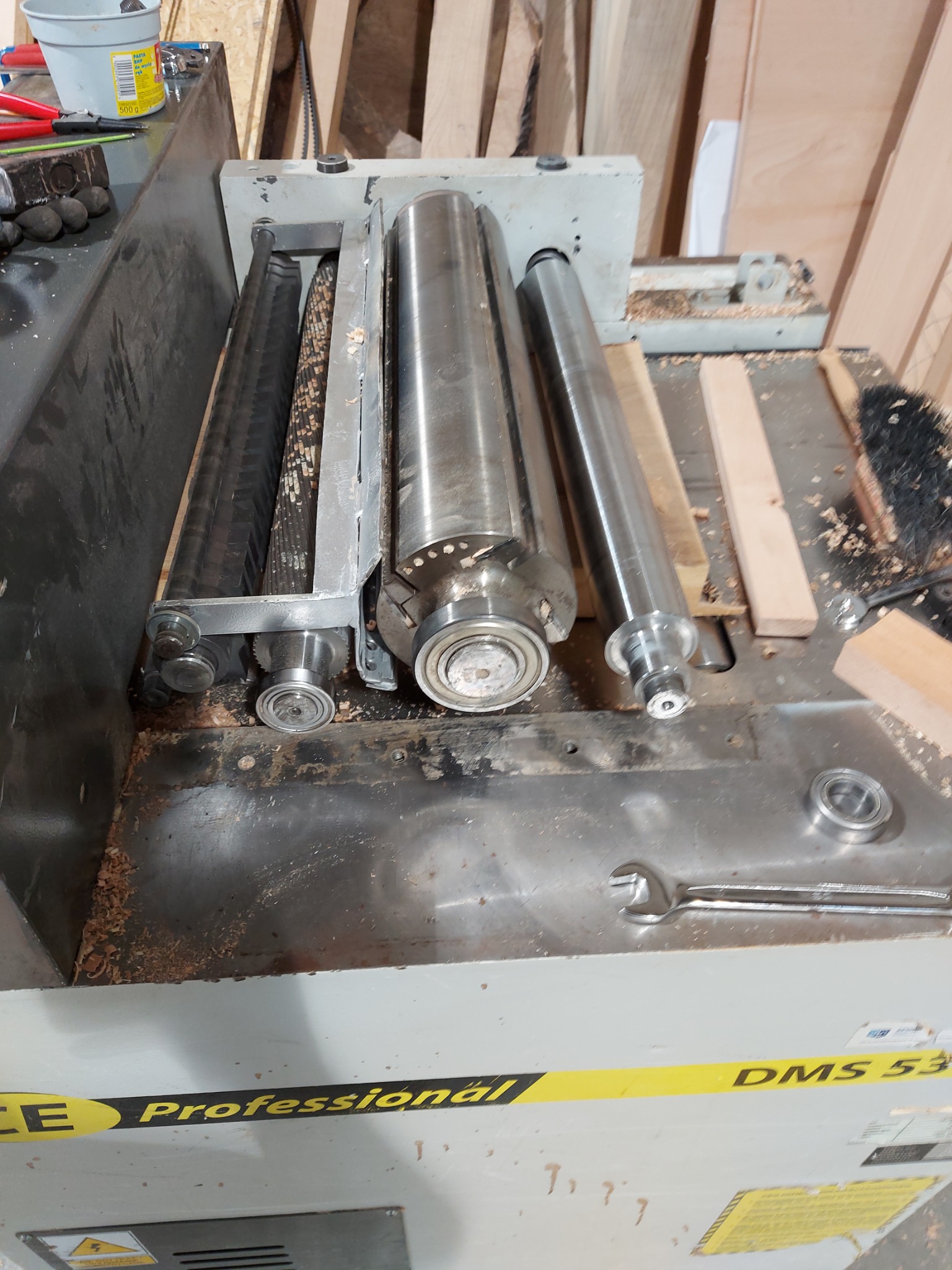Rozłożony wał strugarki grubościówki DMS 53 z widocznymi łożyskami i kluczem płaskim, przygotowany do serwisu.