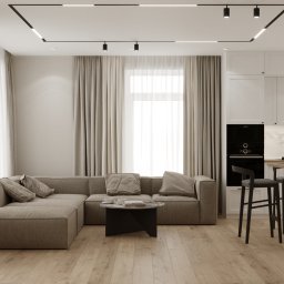 Yurii Fedenko Solutions - Jasne, nowoczesne wnętrze mieszkania z narożną sofą w odcieniach beżu, okrągłym stolikiem kawowym, białymi zasłonami i kuchnią z wyspą oraz hokerami w tle, oświetlone lampami sufitowymi.