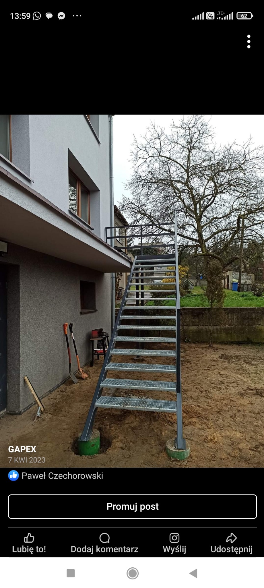 Zewnętrzne schody metalowe z kratownicowymi stopniami prowadzące do balkonu na piętrze domu, osadzone na betonowych fundamentach, widoczne narzędzia budowlane w tle.