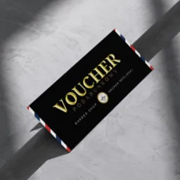 Czarny voucher prezentowy dla barber shopu z napisem 'Voucher Podarunkowy' w złotym kolorze, leżący na szarym, teksturowanym tle.