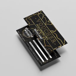 SzelixMedia Julia Szelerska - Dwa eleganckie, czarno-złote vouchery podarunkowe z nazwą 'Przystań Whisky', ułożone pod kątem na jasnoszarym tle, z widocznymi polami do wypełnienia wartości i terminu ważności.