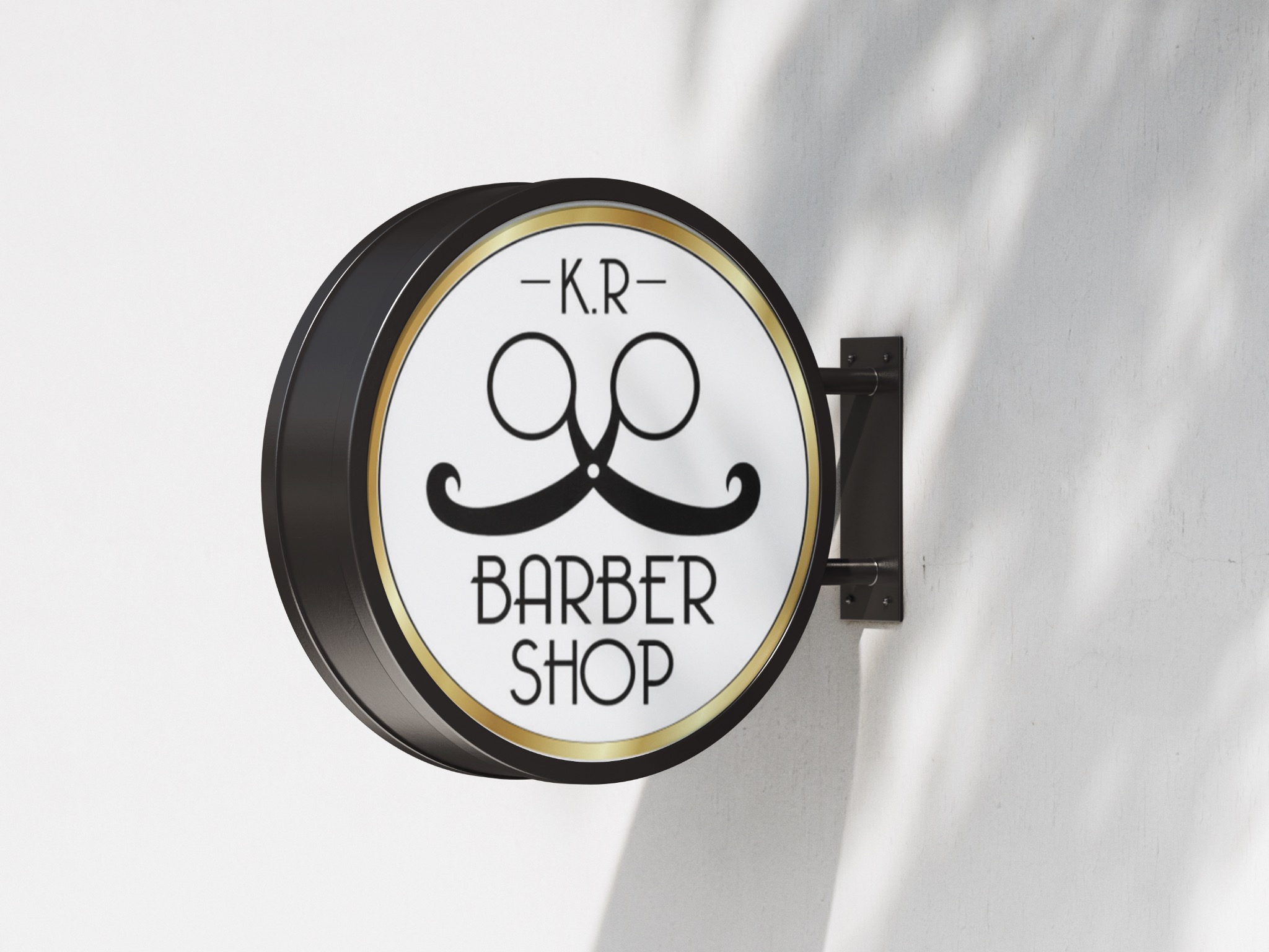 Okrągły szyld z logo salonu fryzjerskiego w stylu retro, przedstawiający nożyczki i wąsy, zamontowany na jasnej ścianie w cieniu liści.