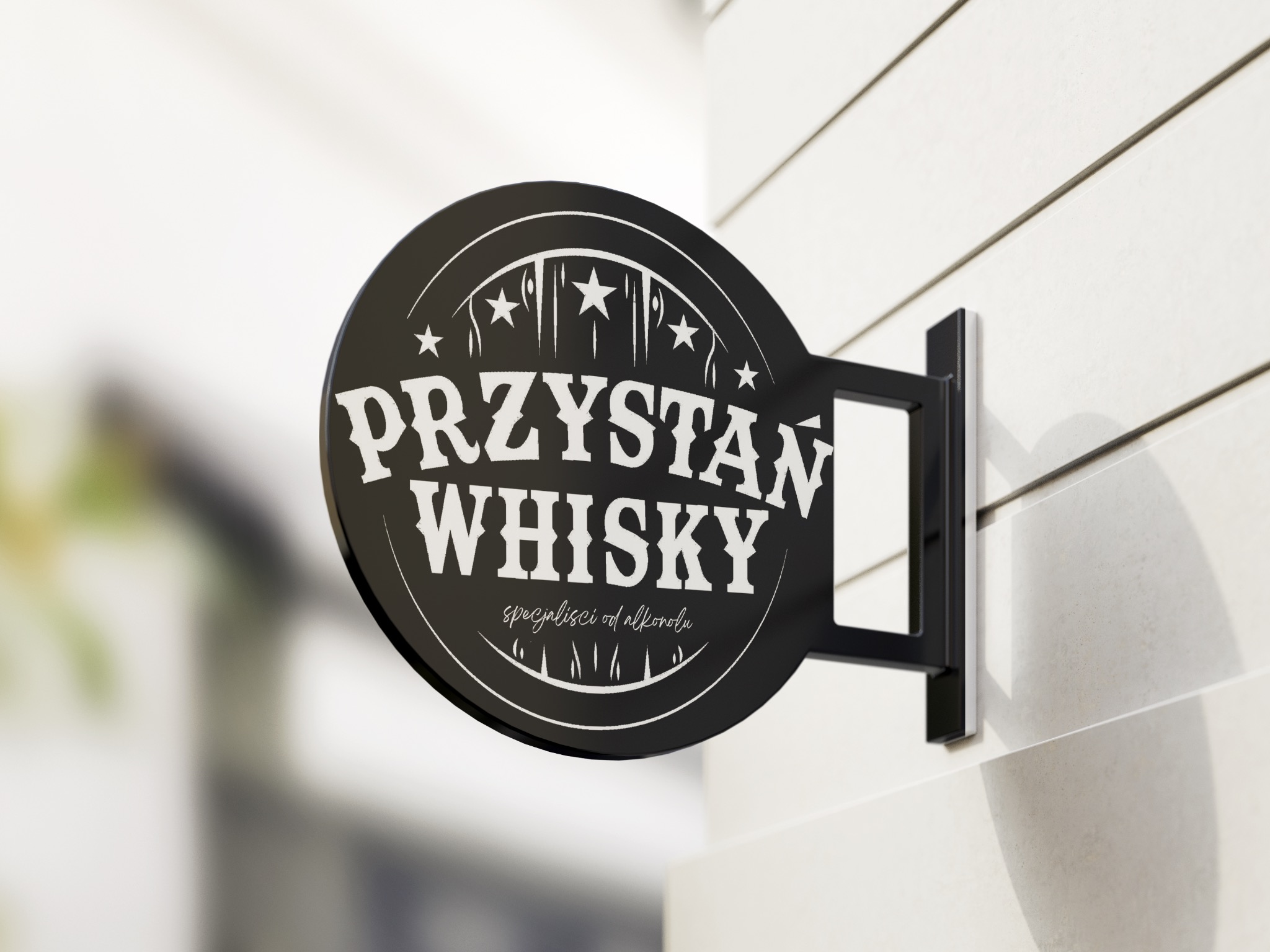 Okrągły, czarny szyld z napisem 'PRZYSTAŃ WHISKY specjaliści od alkoholu' zawieszony na białej ścianie z poziomymi panelami.