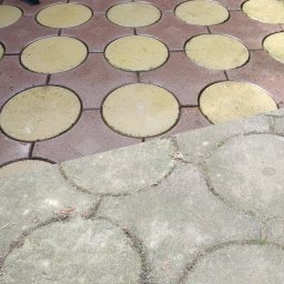 Michał Ostaszkiewicz - Porównanie czystej, mokrej kostki brukowej w kolorze żółtym i brązowym z brudną, suchą, szarą kostką brukową o okrągłym kształcie.