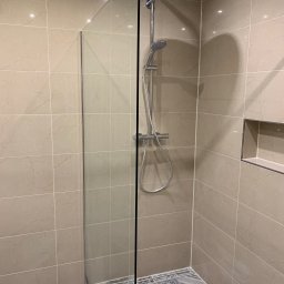 AB Construction - Kabina prysznicowa typu walk-in z chromowaną armaturą i deszczownicą, beżowe płytki ścienne imitujące marmur, dekoracyjna mozaika podłogowa z motywami geometrycznymi i kwiatowymi, wnęka ścienna...