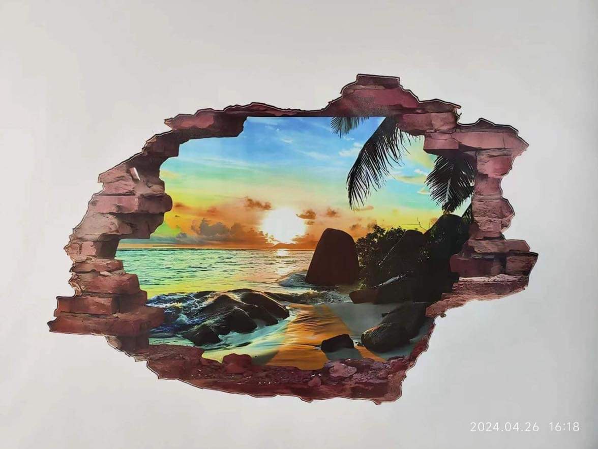 Fototapeta 3D imitująca dziurę w ścianie, z widokiem na tropikalną plażę o zachodzie słońca, otoczoną kamieniami i palmą.