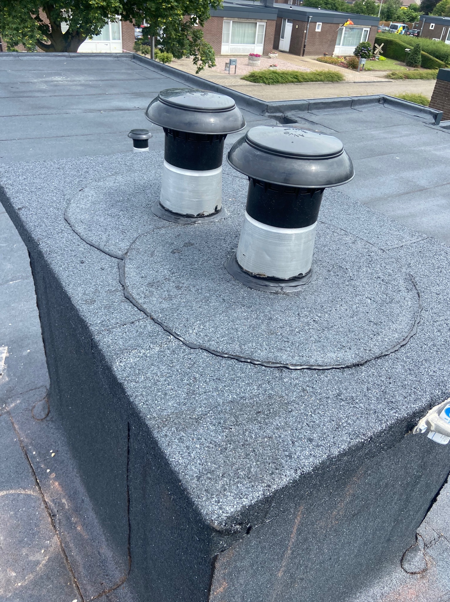 Płaski dach pokryty papą z dwoma kominkami wentylacyjnymi, widoczne uszczelnienia wokół podstawy kominków.