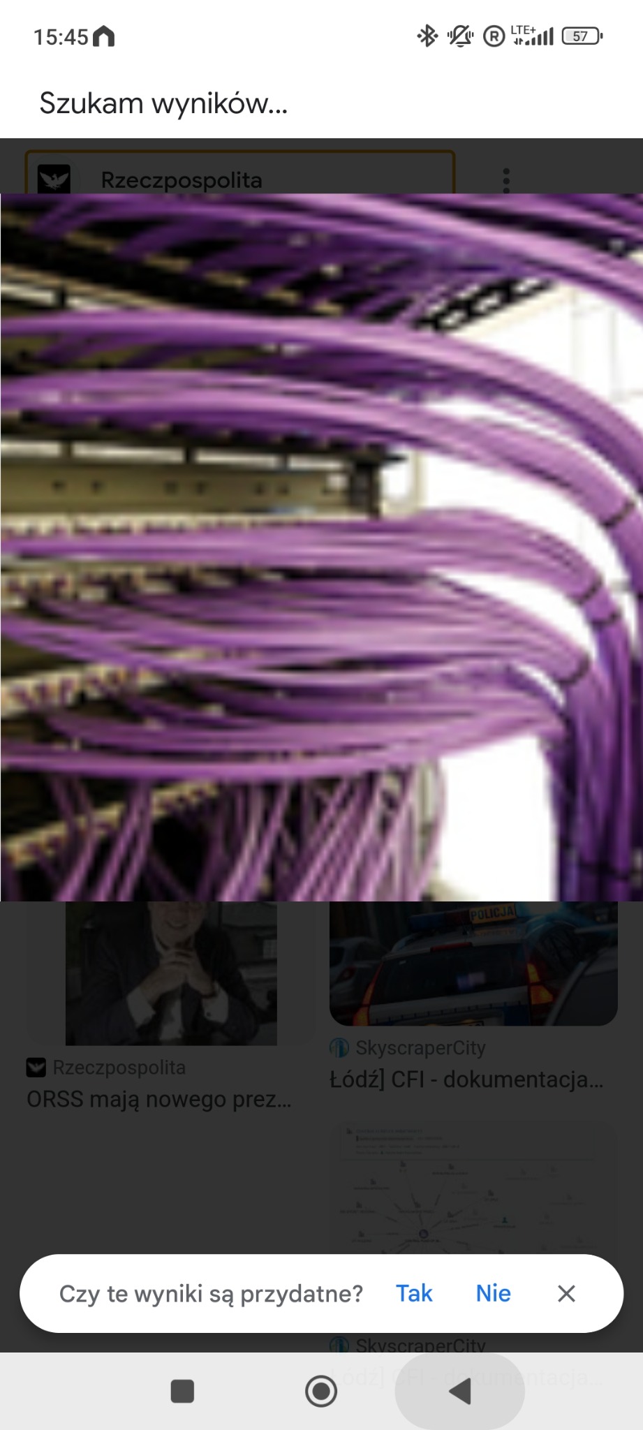 Fioletowe kable sieciowe uporządkowane w szafie serwerowej, widoczne elementy montażowe, lekki efekt rozmycia.