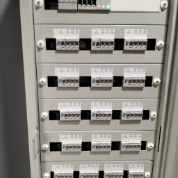 RTD TECHNOLOGY Robert Liberek - Szara szafa rozdzielcza z bezpiecznikami i oznaczeniami, zamontowana w Płocku. Widoczne liczne wyłączniki nadprądowe i różnicowoprądowe.