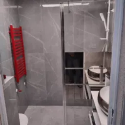 Nowoczesna łazienka z szarymi płytkami imitującymi marmur, kabiną prysznicową typu walk-in z chromowanymi profilami, czerwonym grzejnikiem drabinkowym i podwieszaną umywalką.