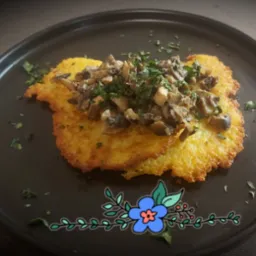 Ziemniaczane placki z sosem grzybowym i posiekaną pietruszką na czarnym talerzu z dekoracyjnym motywem kwiatowym