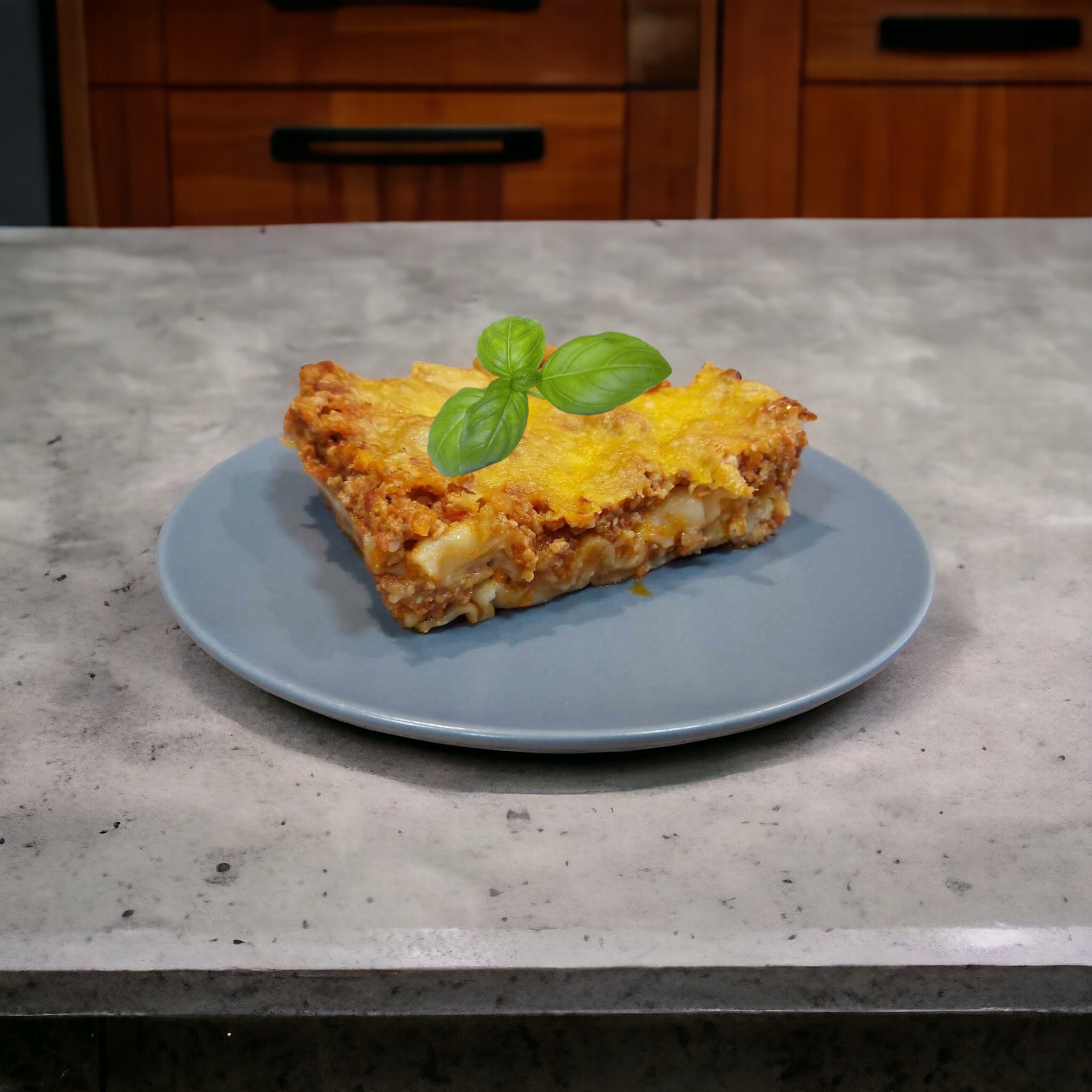 Porcja domowej lasagne z wołowiną i sosem beszamelowym, udekorowana świeżą bazylią na szaro-niebieskim talerzu, na tle blatu kuchennego i drewnianych szafek.