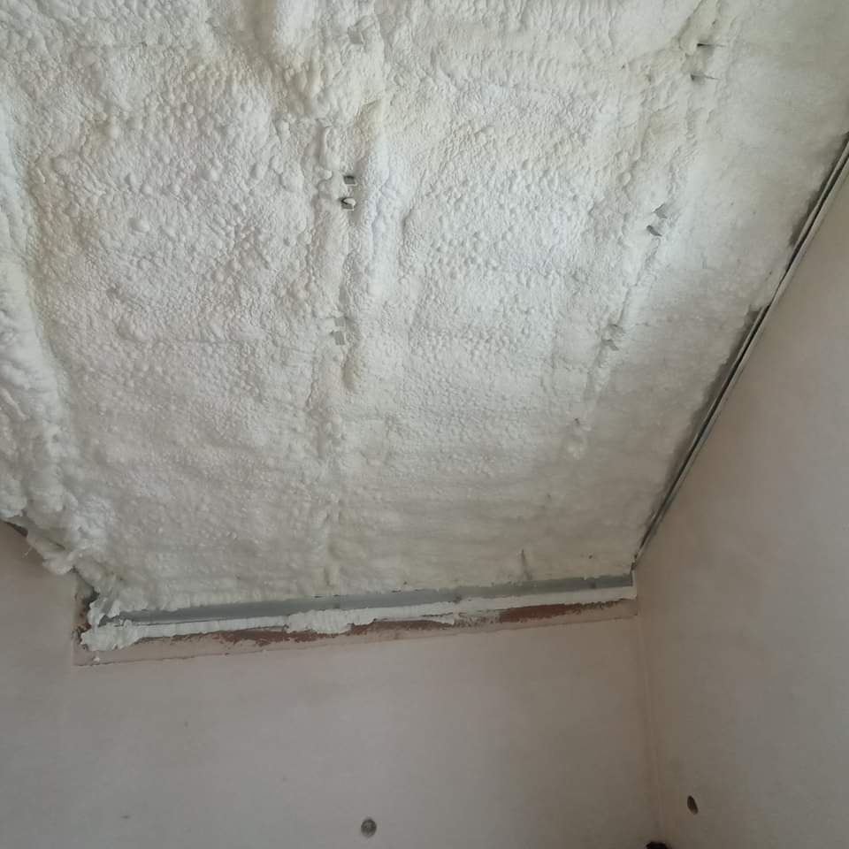 Ocieplenie poddasza pianką PUR z widocznymi metalowymi profilami konstrukcyjnymi i wystającymi elementami mocującymi w pianie.