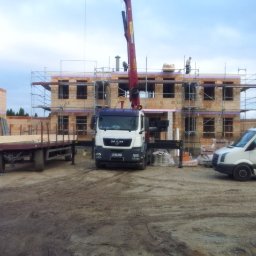 Bau4u - Wznoszenie dwukondygnacyjnego budynku z pustaków ceramicznych, z użyciem dźwigu samochodowego i rusztowań, widoczny pracownik przyczepy i samochód dostawczy z reklamą firmy budowlanej.