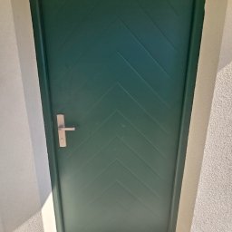 PUERTA DRZWI - Zielone drzwi zewnętrzne z poziomym wzorem w jodełkę i srebrną klamką, zamontowane w białej ścianie z fakturą.