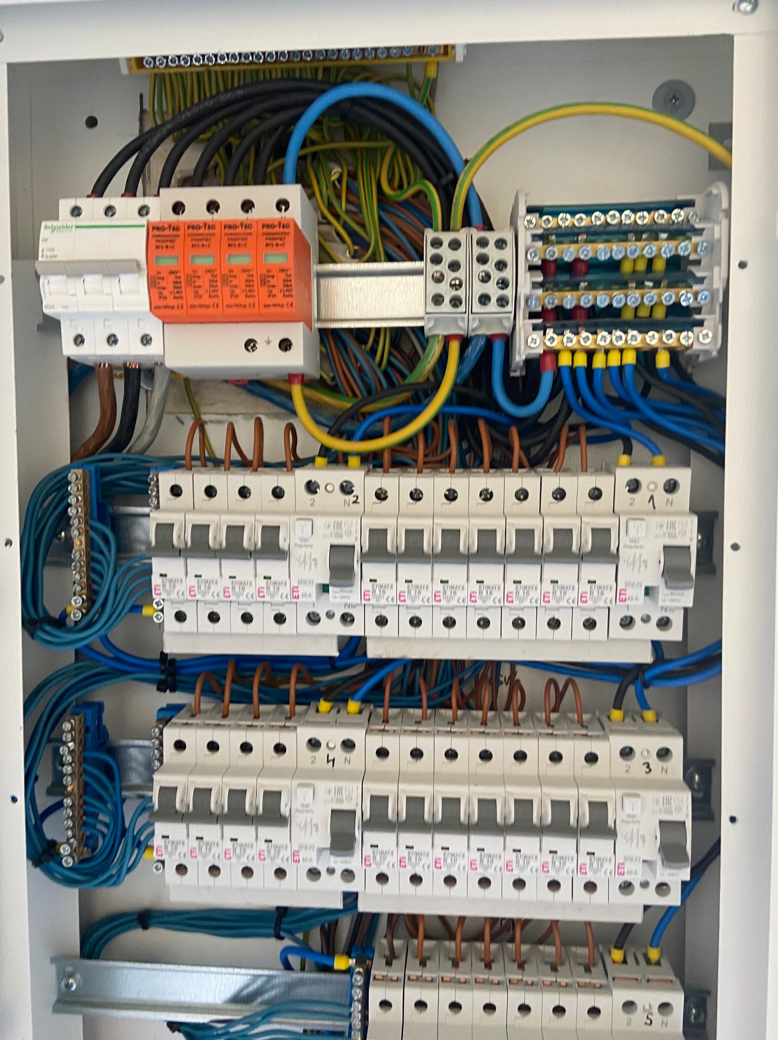 Wnętrze skrzynki elektrycznej z zabezpieczeniami, przewodami w różnych kolorach i listwami zaciskowymi, widok z bliska.