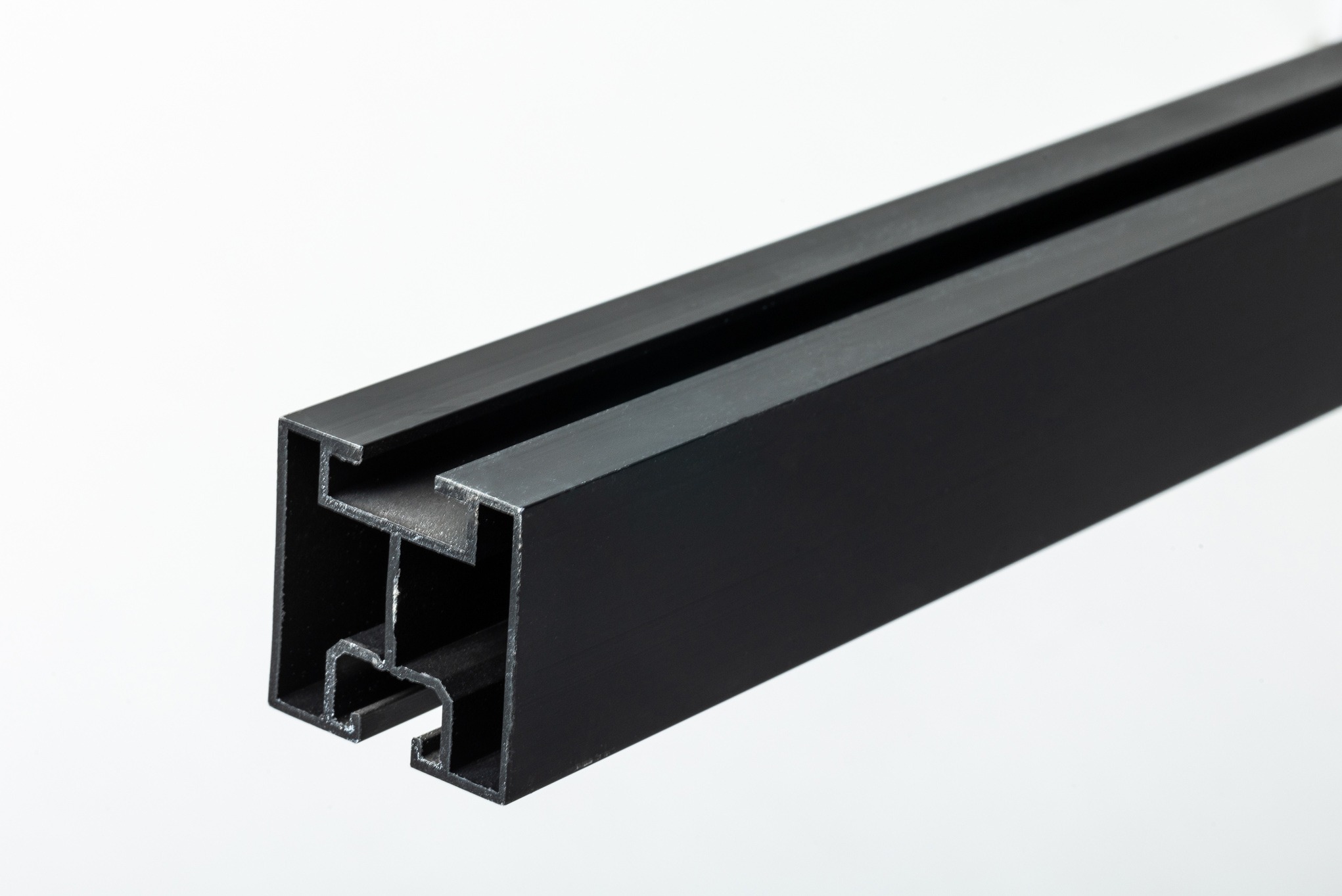 Czarny profil aluminiowy o skomplikowanym przekroju poprzecznym, potencjalnie element konstrukcyjny do montażu paneli.