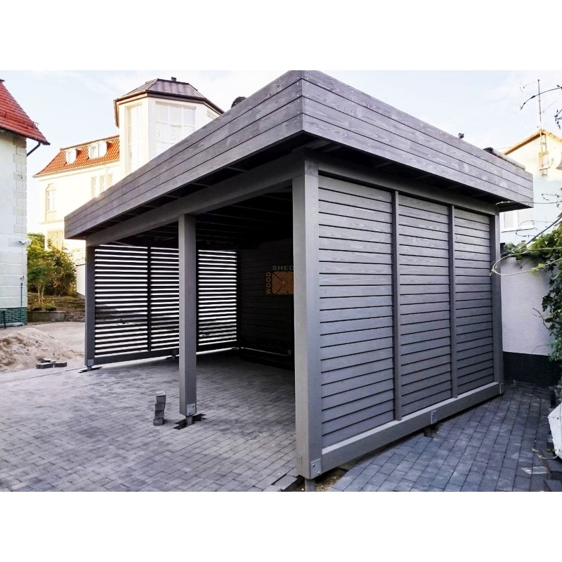 Nowoczesna, szara konstrukcja z drewna z poziomymi panelami i płaskim dachem, prawdopodobnie z przeznaczeniem na garaż lub zadaszenie, na tle brukowanej nawierzchni i zabudowy mieszkalnej.