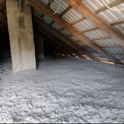 M3 Grażyna Odomirska - Poddasze z widoczną warstwą izolacji z wełny mineralnej, drewniane krokwie i komin z osadami, widok z dołu.