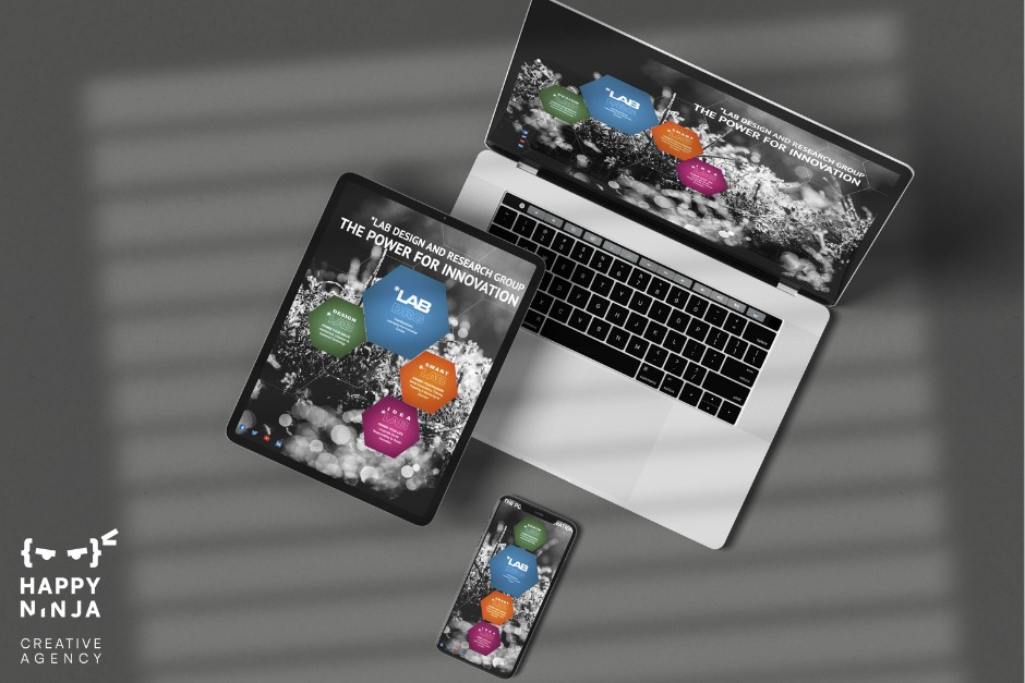 Laptop, tablet i smartfon wyświetlają identyczny interfejs graficzny z heksagonalnymi elementami i hasłem 'LAB DESIGN AND RESEARCH GROUP THE POWER FOR INNOVATION', ułożone na szarym tle z cieniem.