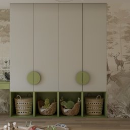 Karols Interiors - Beżowa szafa z zielonymi akcentami w pokoju dziecięcym, z wiklinowymi koszami w otwartych półkach i drewnianą kolejką na podłodze, tapeta z motywem leśnym w tle.