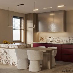 Karols Interiors - Nowoczesna kuchnia z marmurowym blatem, burgundowymi szafkami i drewnianym stołem z czterema jasnymi krzesłami, oświetlona wiszącymi lampami liniowymi.