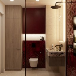 Karols Interiors - Nowoczesna łazienka z kabiną prysznicową walk-in, umywalką z marmurowym blatem, toaletą podwieszaną na tle bordowych płytek i szafką z drewnopodobnym wykończeniem.
