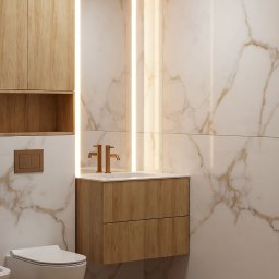Studio Sawubona - Nowoczesna łazienka z drewnianą szafką pod umywalką, złotą armaturą i marmurowymi płytkami. Oświetlenie LED podkreśla elegancki design.