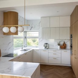 Studio Sawubona - Nowoczesna kuchnia w bieli i drewnie z marmurowym blatem i ścianą. Oświetlenie punktowe z trzema kulami. Parkiet w jodełkę. Minimalistyczny design.