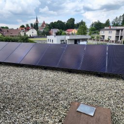 Avotech - Panel słoneczny na żwirowym dachu z widokiem na miasteczko i kościół w tle.