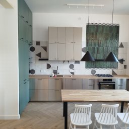 Serra's team Zakład Budowlany Rafał Serafin - Nowoczesna kuchnia z zielonymi i beżowymi szafkami, drewnianym blatem i stołem. Na ścianie dekoracyjne płytki w geometryczne wzory i zielona mozaika.