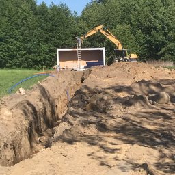 KOFI TRADE SPÓŁKA Z OGRANICZONĄ ODPOWIEDZIALNOŚCIĄ - Wykop w Prusicach z ułożonym niebieskim przewodem, w tle kontener budowlany i koparka, dwóch pracowników przy kontenerze.