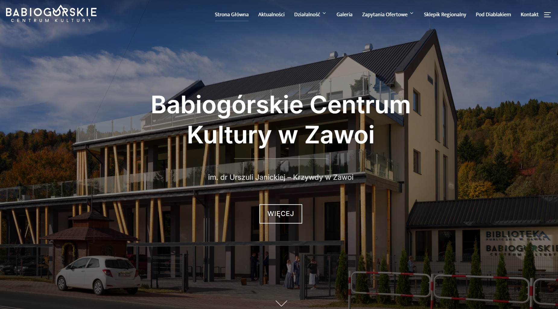 Strona internetowa Babiogórskiego Centrum Kultury w Zawoi. Widok na budynek, menu nawigacyjne u góry, przycisk 'Więcej' i logo biblioteki w prawym dolnym rogu.
