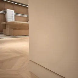 Fragment wnętrza z parkietem ułożonym we wzór jodełki francuskiej, widoczna ściana w kolorze kremowym i fragment mebli w tle.