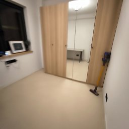Pruzo Marek Strzała - Pokój z beżową podłogą, jasnymi ścianami i szafą z lustrzanymi drzwiami; odkurzacz pionowy stoi przy ścianie.