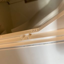 Magiczny blysk - Brudny, biały pojemnik na detergenty w pralce, widoczne resztki proszku i zabrudzenia. Perspektywa z góry, oświetlenie naturalne.