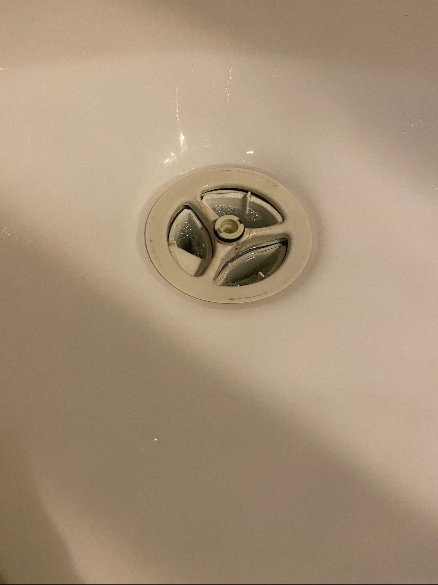 Biała umywalka z odpływem, widoczne ślady użytkowania i lekkie zabrudzenia.