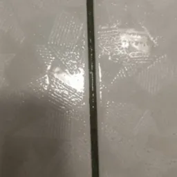 Zbliżenie na mokre, białe płytki z ciemną fugą, pokryte kroplami wody po czyszczeniu.