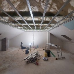 Mykhailo Lavryshyn V&M Construction - Poddasze w trakcie adaptacji: widoczne metalowe profile sufitowe, izolacja z piany, częściowo zamontowane płyty gipsowe. Na podłodze narzędzia i materiały budowlane.