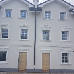 ZK HOUSE ANNA OTOLIŃSKA - Odnowiona elewacja bliźniaka z dekoracyjnymi obramowaniami okien i drzwi, świeżo pomalowana na jasny kolor. Widoczne numery budynków 39 i 39A.