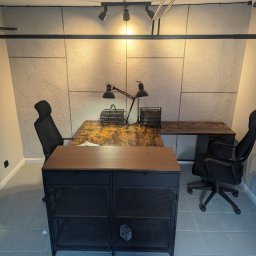 New Structure - Biuro z drewnianym blatem i metalowymi elementami, oświetlone lampami biurkowymi, na tle ściany z dekoracyjną fakturą betonu.