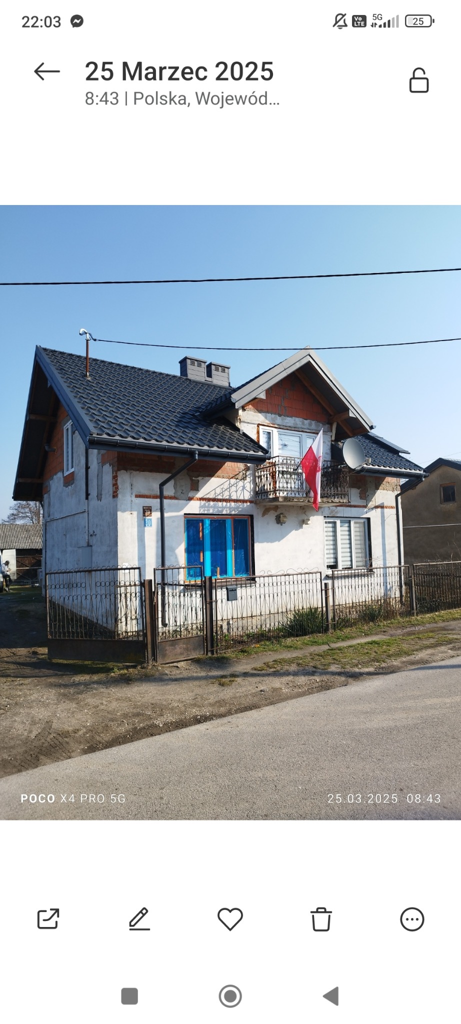 Dom jednorodzinny w trakcie prac remontowych elewacji, widoczne fragmenty cegły, okna zabezpieczone folią, balkon z polską flagą, nowa dachówka.