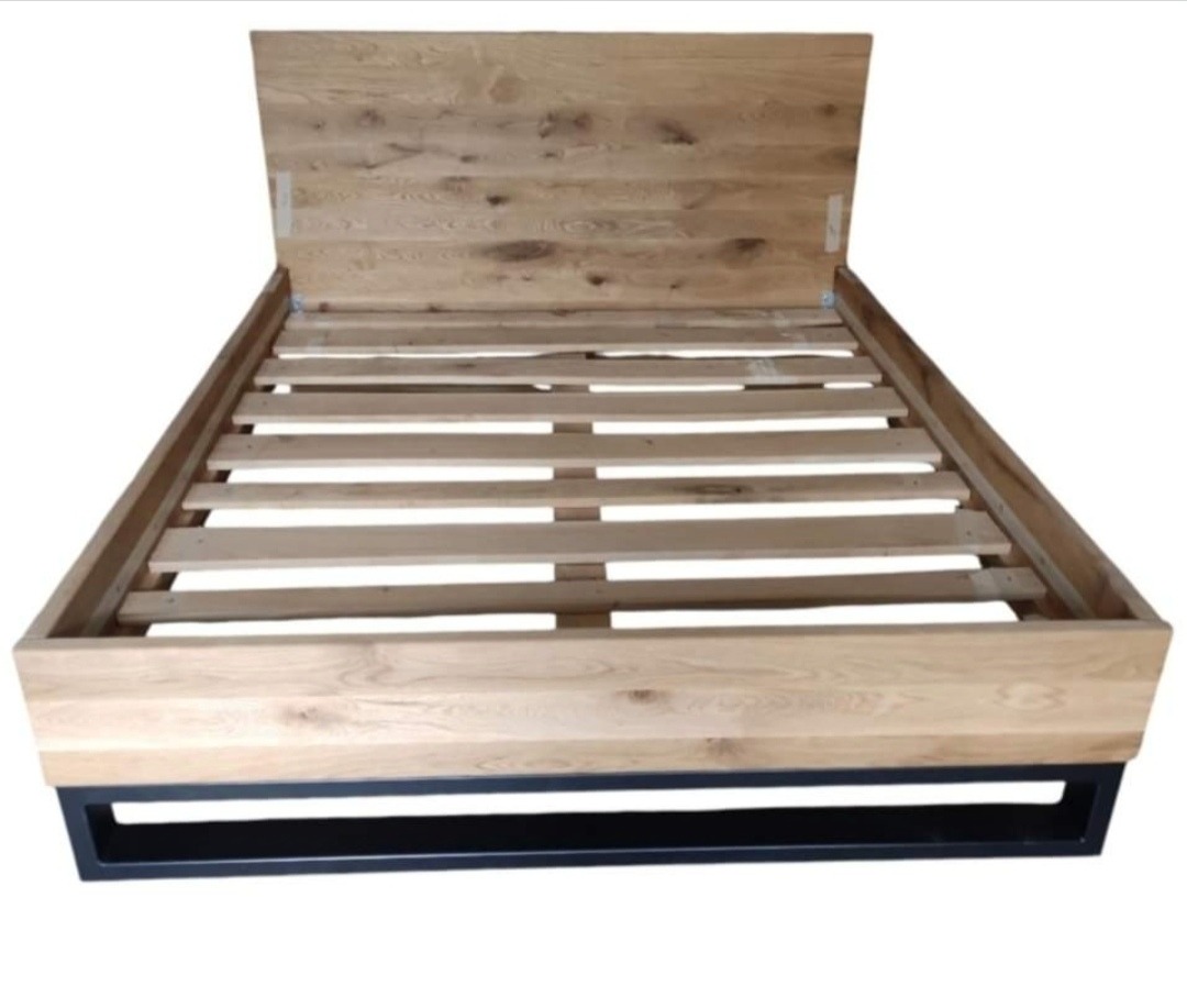 Rama łóżka z drewna o jasnym odcieniu, z czarną metalową podstawą, widok z przodu, bez materaca.