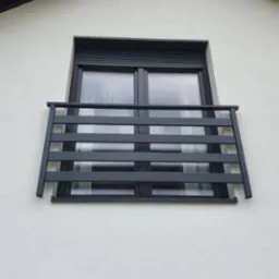 Nowoczesna, szara balustrada okienna z poziomych profili, zamontowana na białej elewacji budynku. Okno z roletą zewnętrzną, ujęcie od dołu.